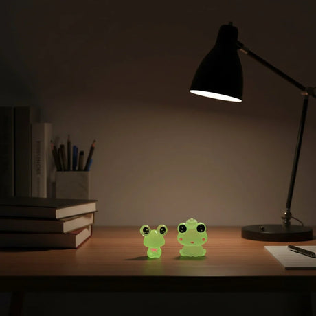 Miniature Resin Mini Frog Assorted (1Pc) displayed on a desk under a lamp.