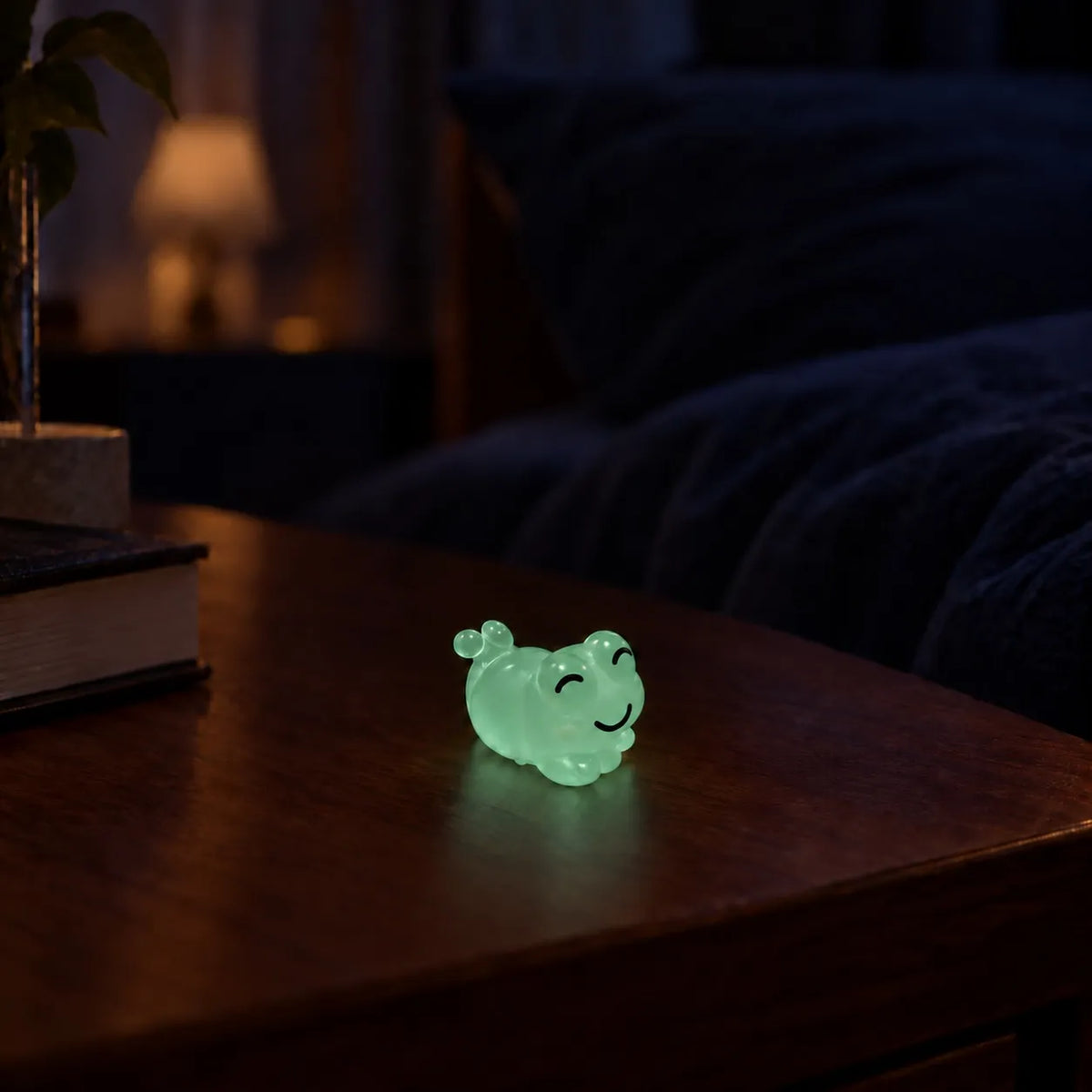 Miniature Glow Cute Resin Frog Assorted (1pc) glowing on a wooden table in a dimly lit room