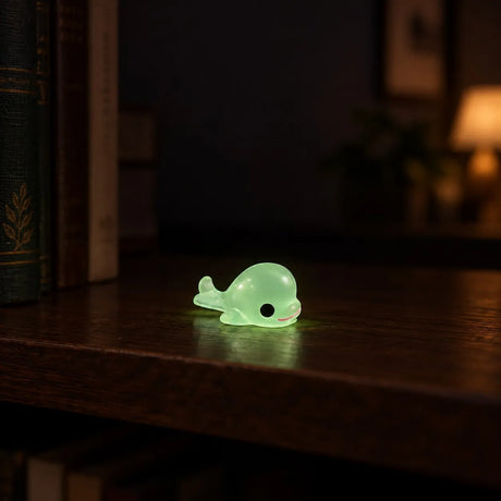 Miniature Glow Dolphin Assorted (1pc) glowing on a wooden table in a dark setting