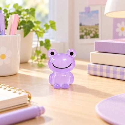 Miniature Glow Frog Assorted (1pc) displayed on a desk near a window with books and stationery