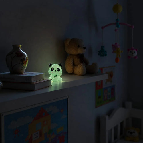 Miniature Glow Panda Assorted (1pc) glowing on a shelf in a dimly lit room