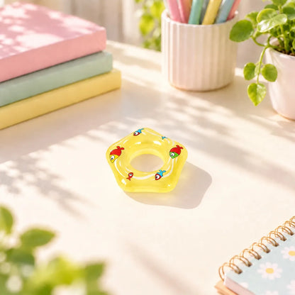 Miniature Glow Floating Swimming Ring Assorted (1pc) displayed on a desk near a window with books and stationery